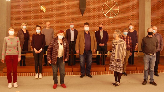 En gruppe mennesker står sammen i en kirke, alle med ansigtsmasker.