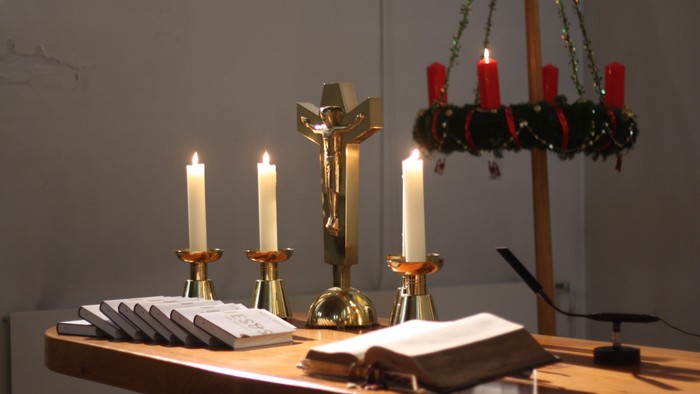 Weihnachtsdekoration mit brennenden Kerzen und Kreuz