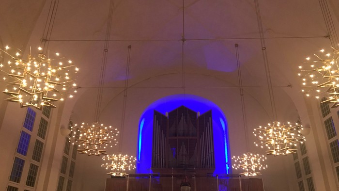 Indre del af kirke med belysede lysstærner og orgel