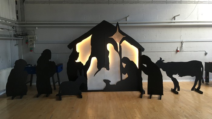 En skyggekast af julekrybde med figurer i en hall.