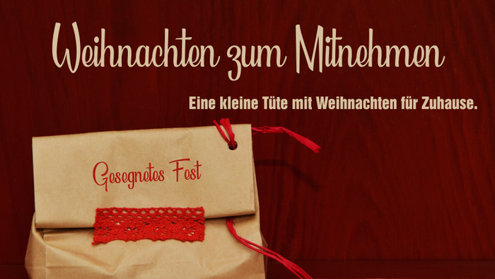Eine kleine Geschenktüte mit der Aufschrift „Geschenkost Fest“, festlichem Weihnachtstext und roter Schleife auf einem Holzuntergrund.