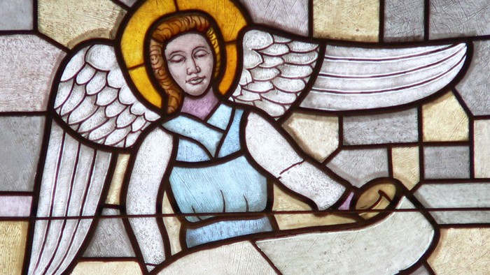 Engel mit Flügeln und Buch in buntem Glasfenster