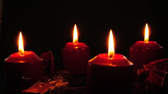 Photo von vier Kerzen auf einem Adventskranz im Dunkel