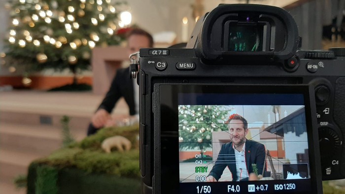 Eine Kamera filmt einen Mann vor einem Weihnachtsbaum