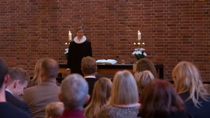 En præst holder en tale for en forsamling i en kirke.