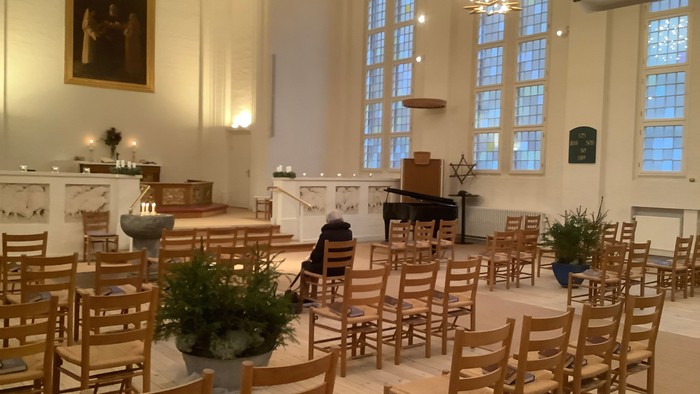 Indre del af kirke med træstole og blomster.