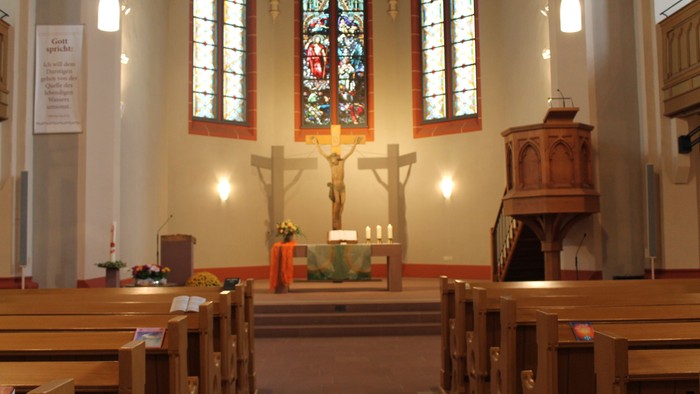Innenraum einer Kirche mit Altarraum und Buntglasfenster