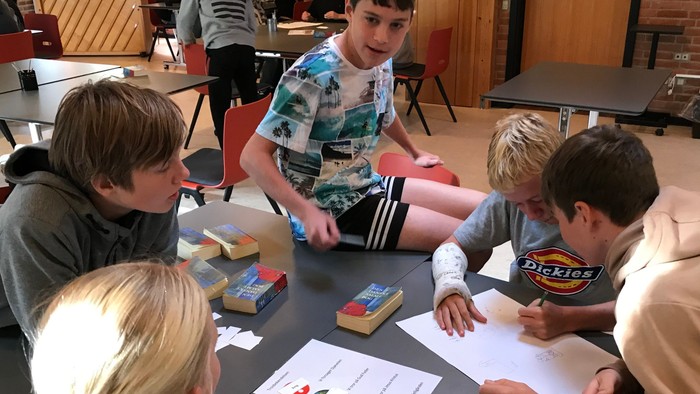 Børn sidder om bordet og ser på en papir.