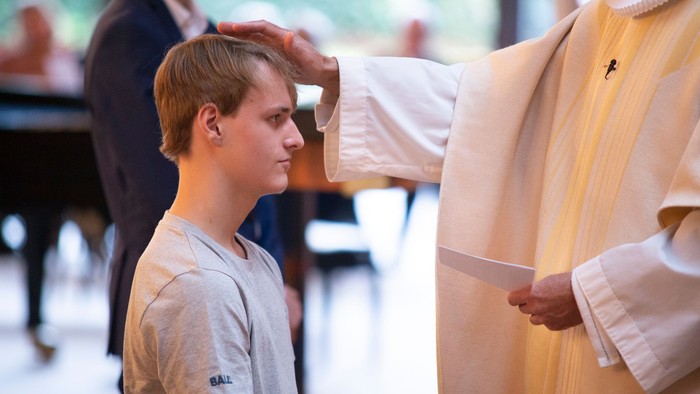 En præst børster en ung drengs hår under en religiøs ceremoni.