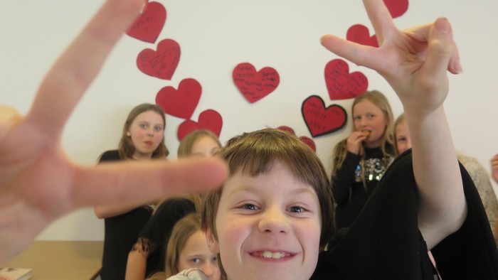 Børn og voksne laver hjerteformer med hænderne.