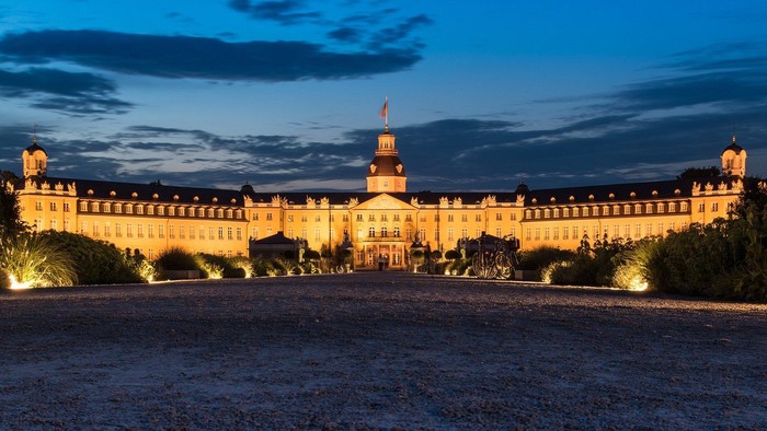 Großes, beleuchtetes Schloss bei Dämmerung mit klarem Himmel