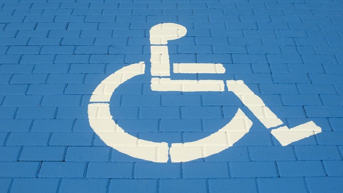 Ein weißes Rollstuhl-Symbol auf blauen Kopfsteinpflastersteinen