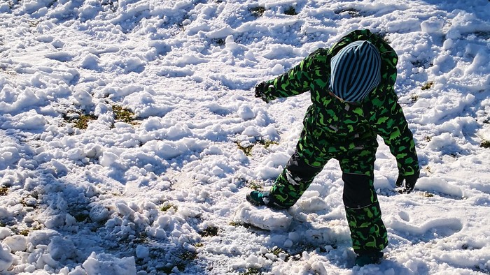 Kind spielt im Schnee vor Haus
