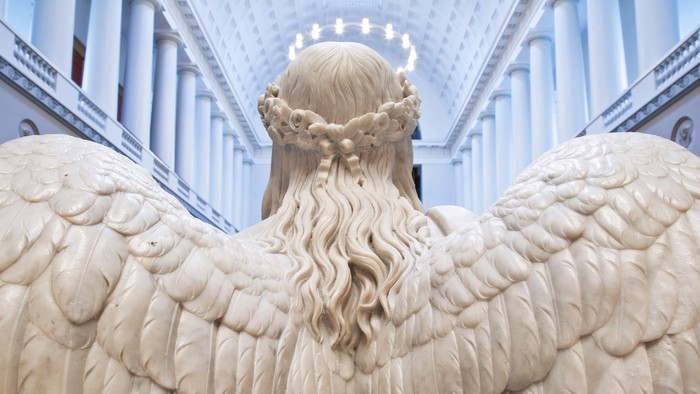En stor, detaljeret skulptur af en engel med udbredte vinger i et indendørs miljø.
