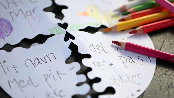 En papir med tegninger og tekster i blyant og fargepensler