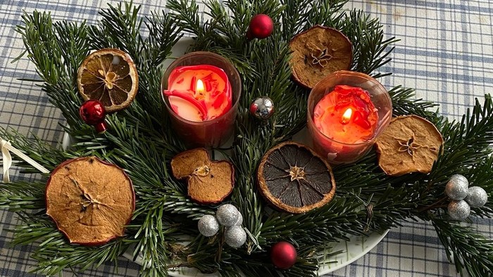 Ferien-Dekoration mit Kerzen, Tannenzweigen und Orangen