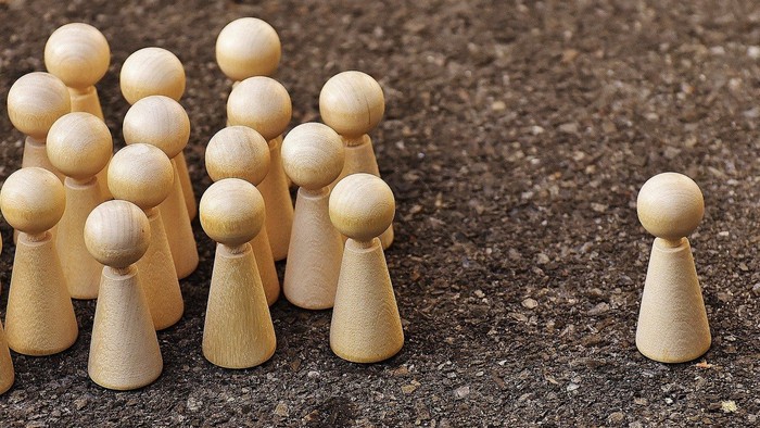 Holzfiguren, eine Gruppe und eine einzelne Figur auf rauer Oberfläche