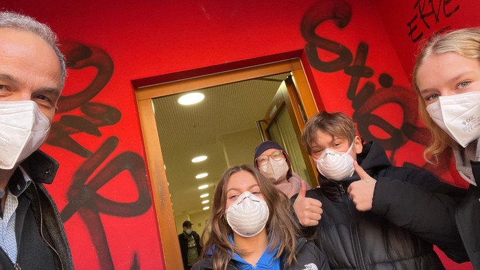 Familie mit Mund-Nasen-Schutz vor rotem Graffiti-Wand