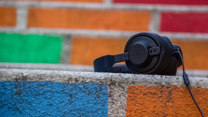 Ein schwarfer Kopfhörer liegt auf einer farbenfrohen Ziegelmauer.