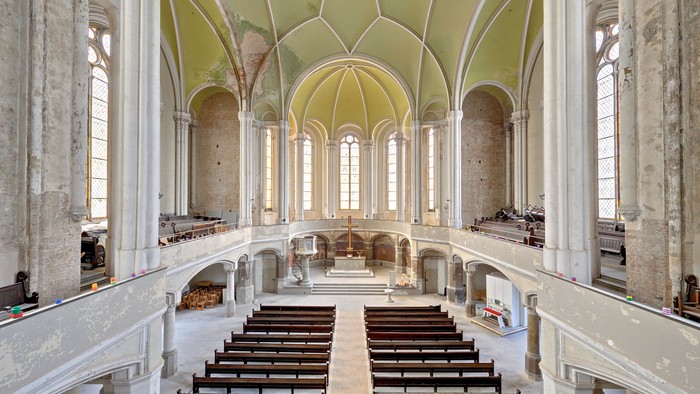 Altes Kircheninnere mit hohen Bögen und Holzbänken
