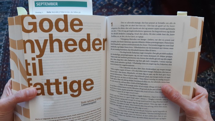 Hænder holder en åben bog med teksten
