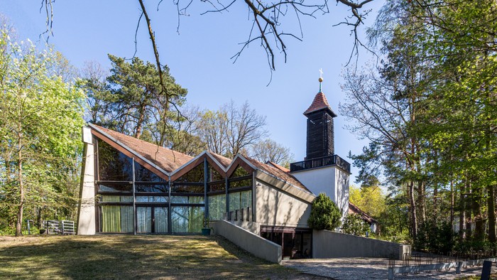 Moderne Kirche mit hohem Turm in ruhiger, grüner Umgebung