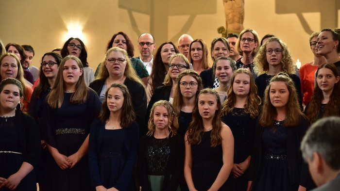 Eine Gruppe von Menschen posiert vor einem großen Kreuz in einer Kirche.
