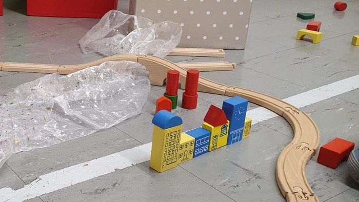 Holzspielzeugbahn mit bunten Blöcken und Plastiktüten auf dem Boden