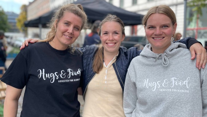 Tre kvinder står sammen med t-shirts med teksten "Hugs & Food".