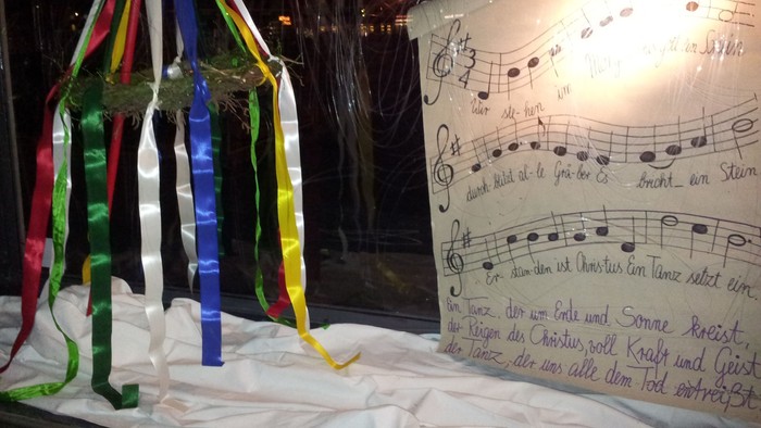 Bunter Maybaum auf weißem Tuch mit Noten und deutschem Text im Hintergrund