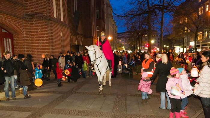 Eine Frau reitet ein weißes Pferd durch eine belebte Stadtstraße bei Nacht.