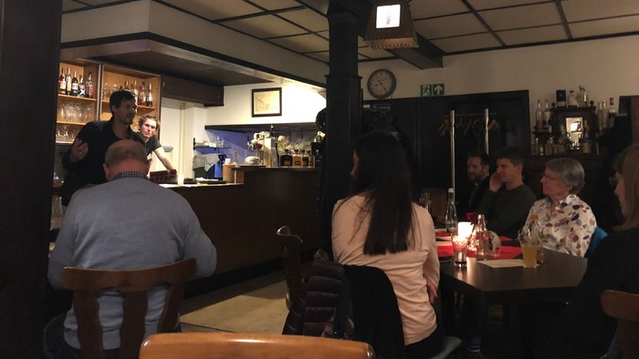 Ein gemütliches Restaurant mit Gästen an Tischen, eine Bedienung hinter der Theke.