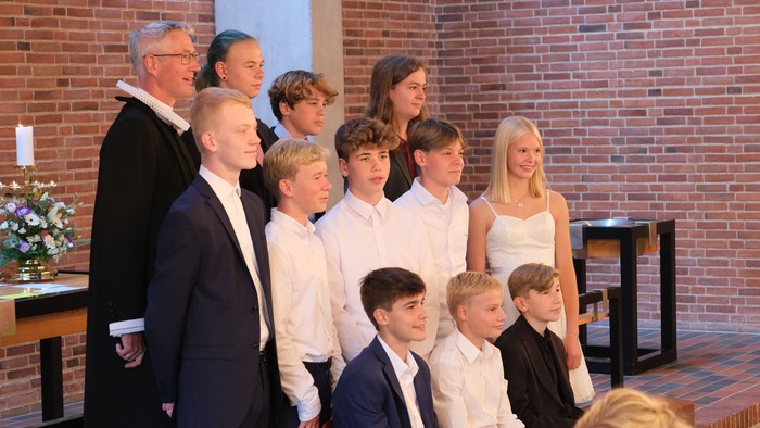 En gruppe af mennesker, inklusive børn, står sammen i en kirke.