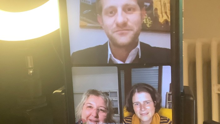 Handy zeigt Videokonferenz mit drei Teilnehmern