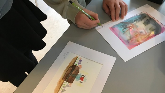 Børn tegner på papir med blyant.