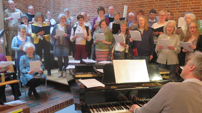 En gruppe af mennesker synger i kor med en pianist.