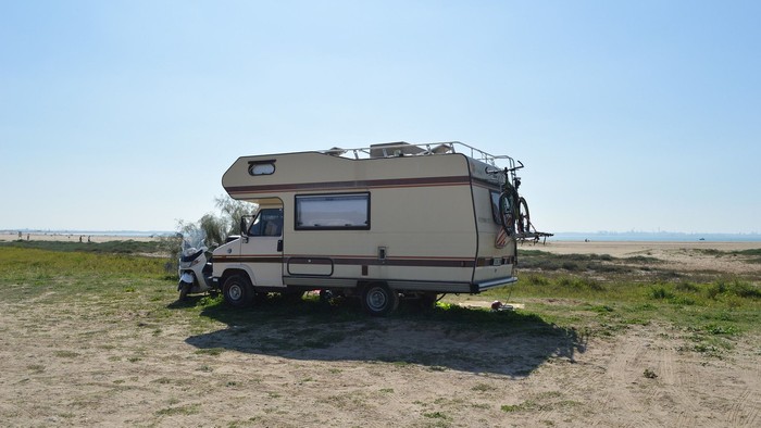 Ein Wohnmobil steht auf einem Feld neben dem Meer.