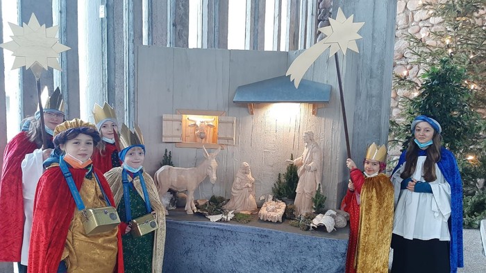 Kinder in Kostümen um eine Krippe bei einer Weihnachtsfeier