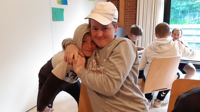 To børn hugger hinanden i en klassesal.