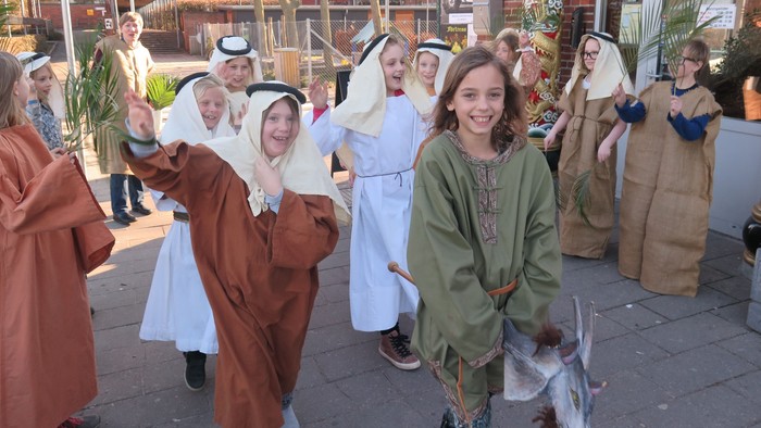 En gruppe børn i historiske kostumer danser på gaden