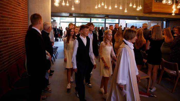 En gruppe af formelt tøjede mænd og kvinder samles i et lysende og moderne indendørs område.