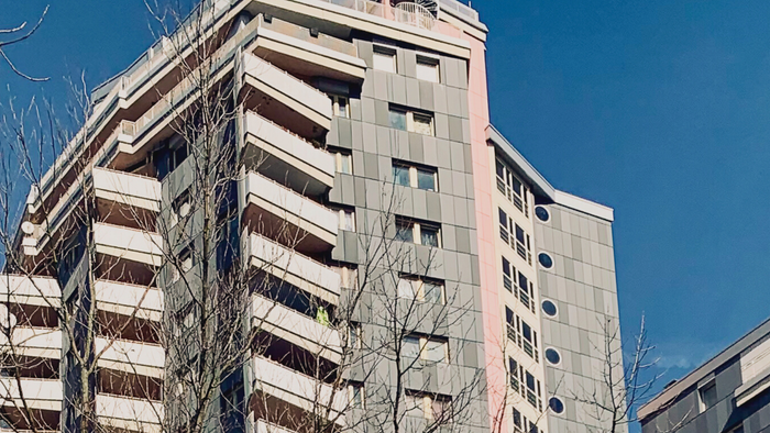 Zwei hohe, ältere Wohnblöcke vor klarem blauem Himmel.