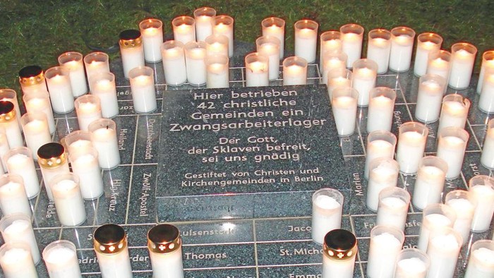 Rund um ein Gedenkstein stehen viele brennende Kerzen.