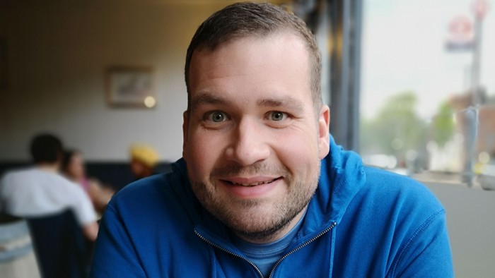 Man in blue jacket smiling.