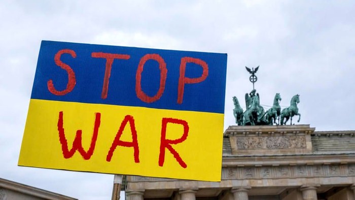 Protestschild mit "STOP WAR" vor Brandenburger Tor