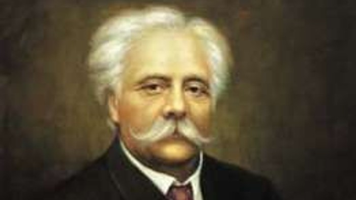 Ein älterer Mann mit weißem Bart und dunklem Anzug.