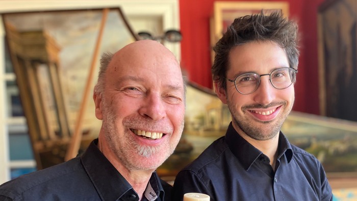 Zwei Männer lächeln, einer hält eine Flöte