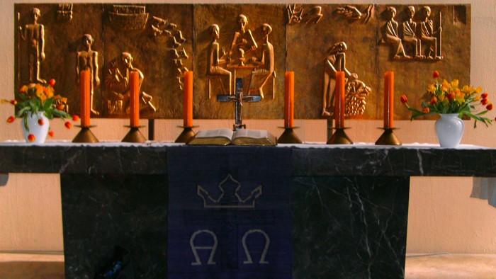 Altar mit Kerzen, Blumen und goldenen Reliefs