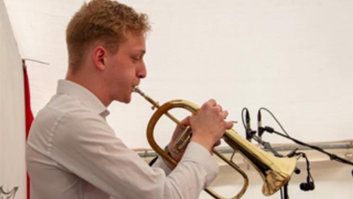 En ung mand spiller trompet i et studio.