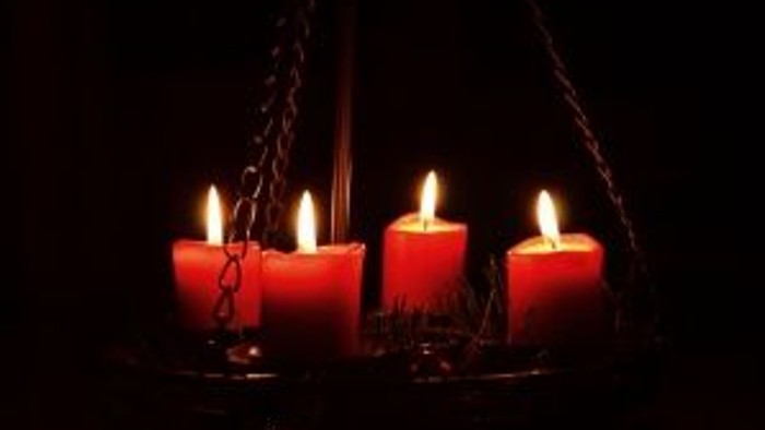 Vier brennende Kerzen in dunkler Umgebung